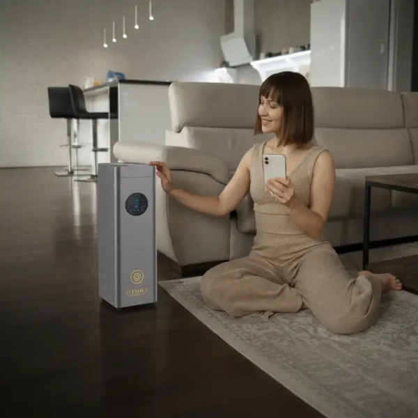Woman using smartphone app to control OTURA ELITE professional large-scale scent diffuser in modern living room